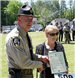 Officer holding plaque next to lady