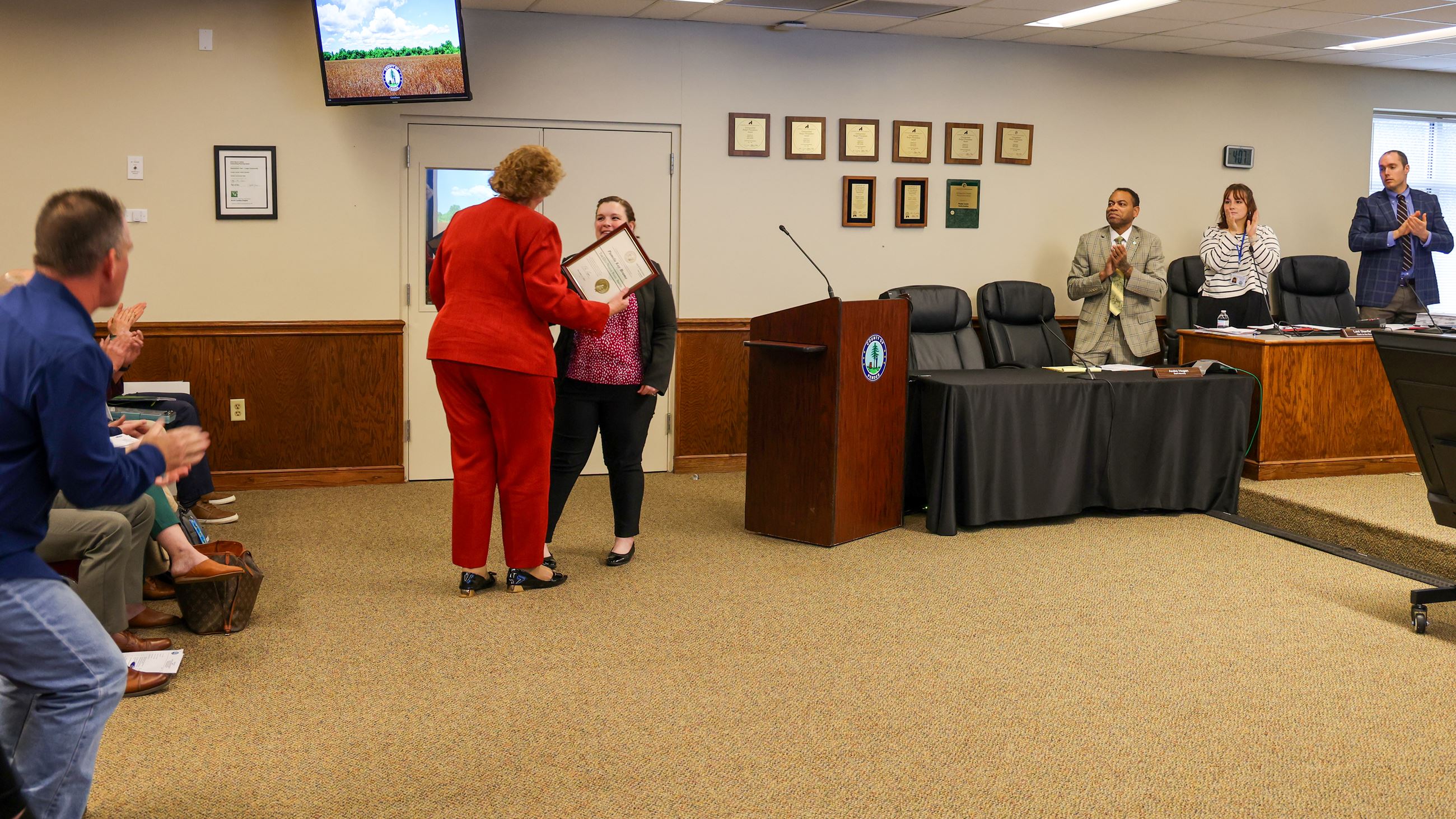 tall woman receiving an award from shorter woman with brown hair